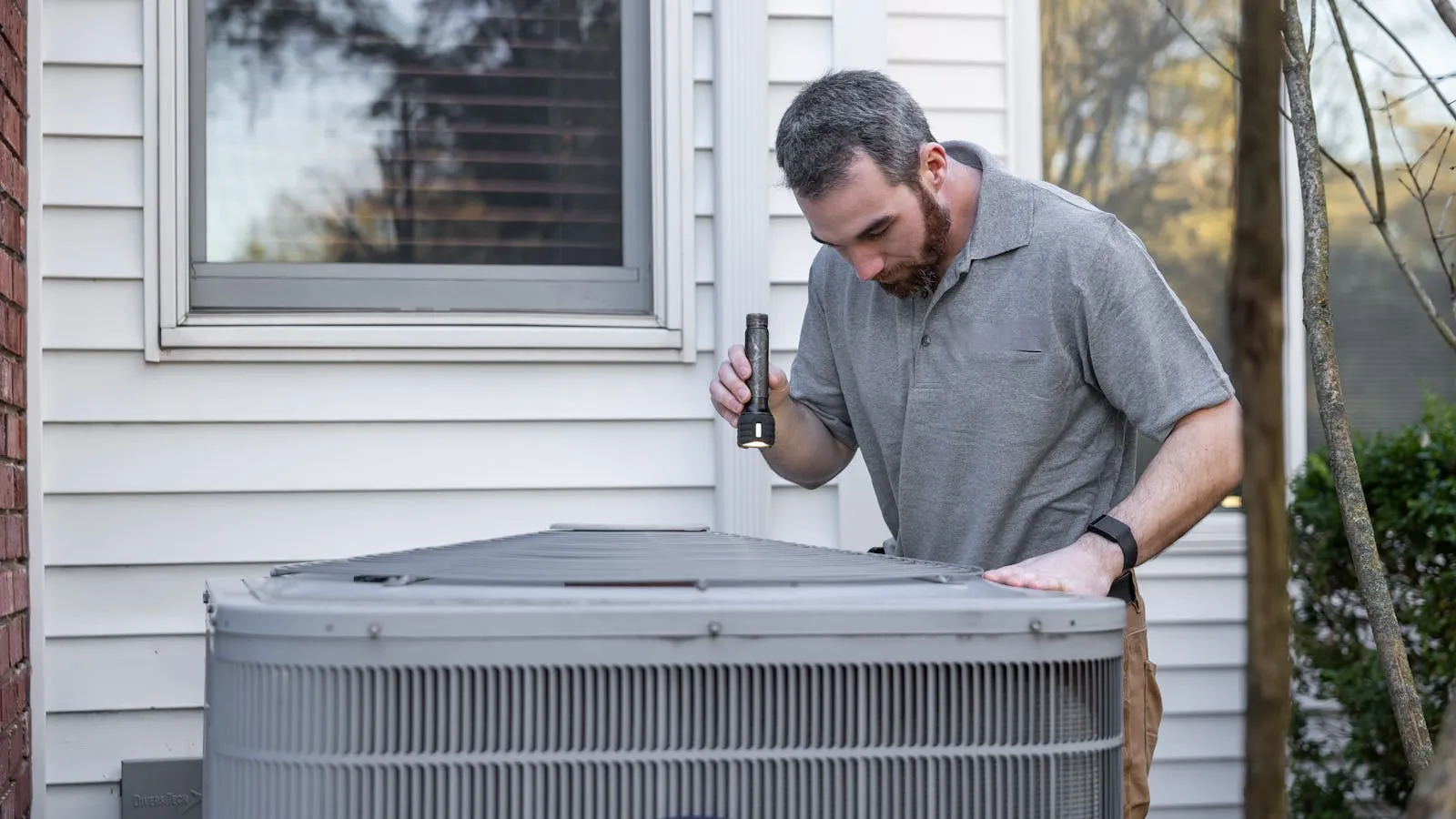 HVAC technician inspecting an outdoor air conditioning unit