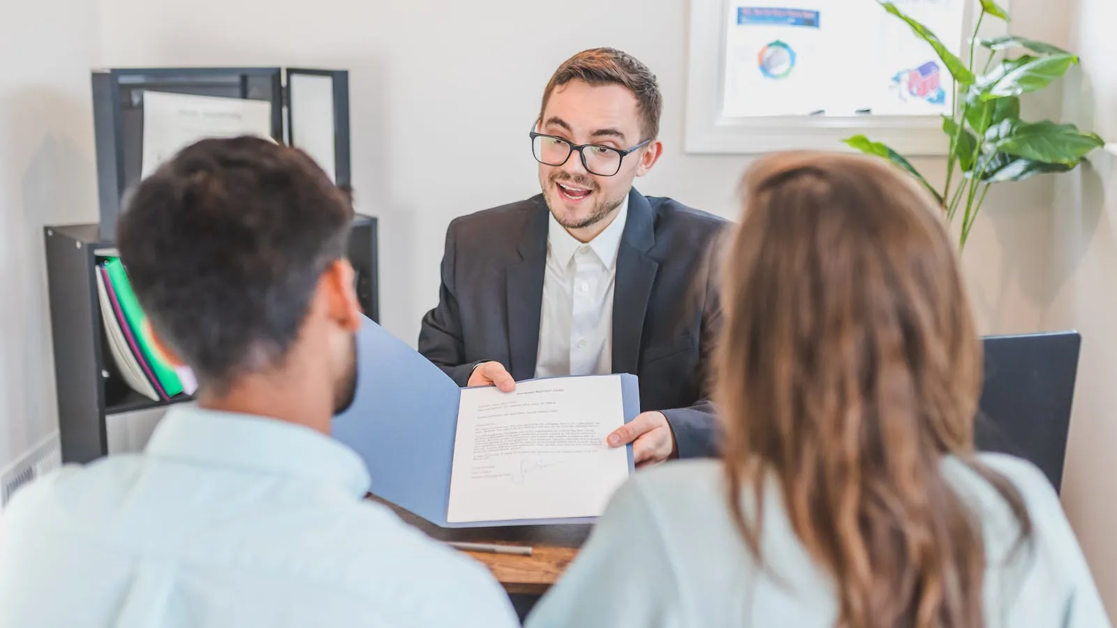 Mortgage broker reviewing loan documents with clients in an office